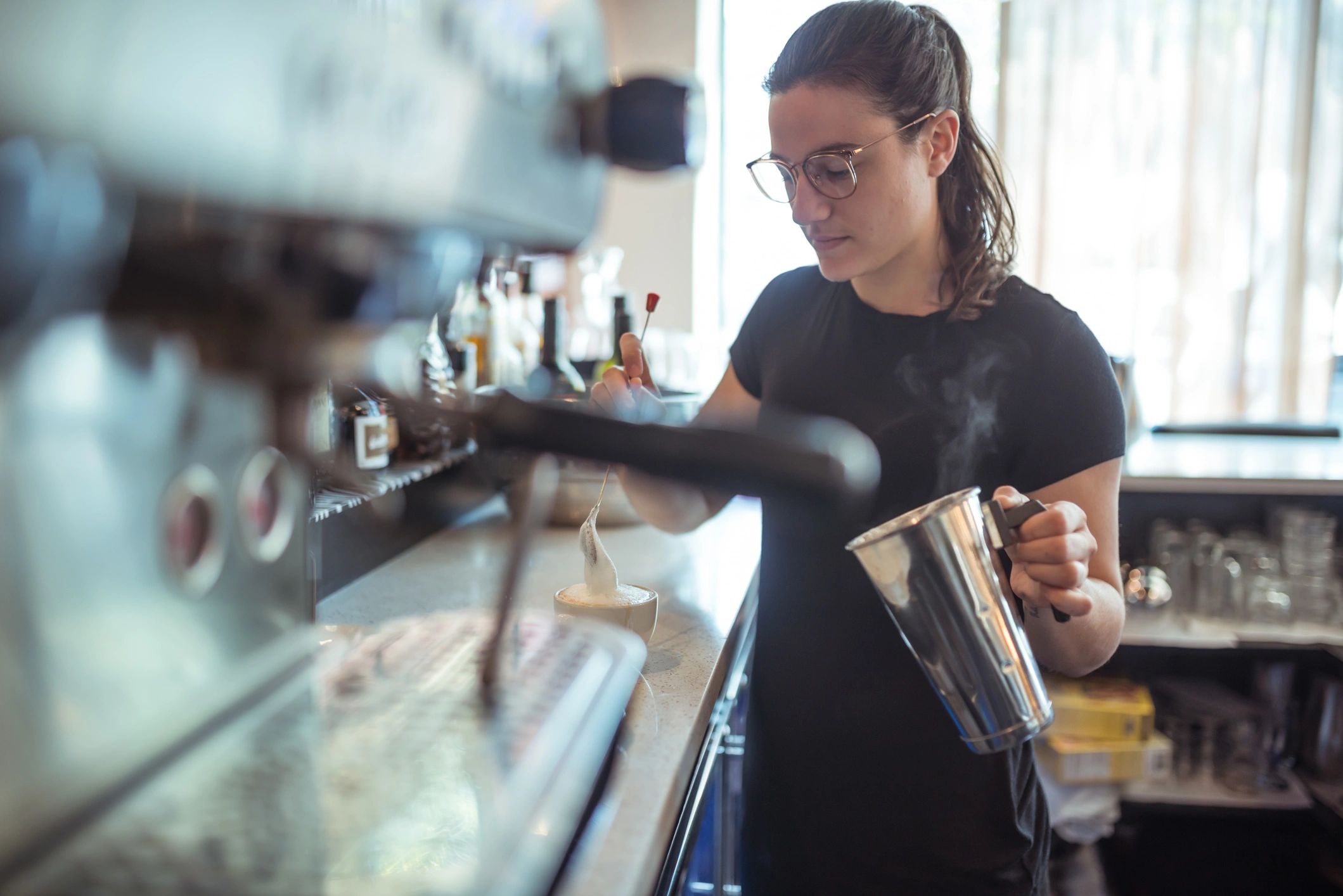 Barista preparing coffee with steamed milk